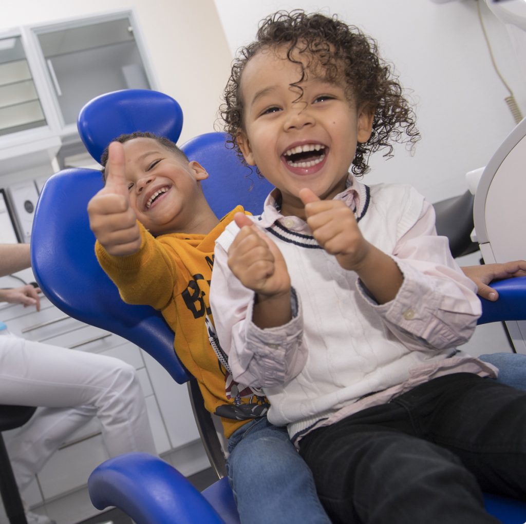 Twee blije kinderen zittend in een tandartsstoel
