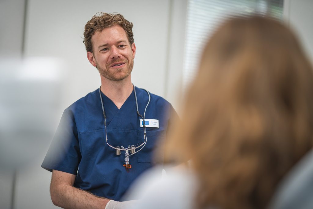 Tandarts voor Orthodontie Joris Jessen lachend naar een patiënte die in de stoel zit